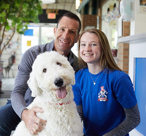 Two people smile with a dog