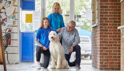 Two employees greet two dogs that have entered an AAPR location