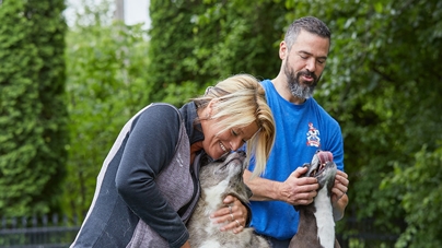Two employees play with dogs outside