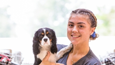 A woman holds a dog up in her arms