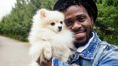 A small white dog being held by a man. A small white dog being held by a man.