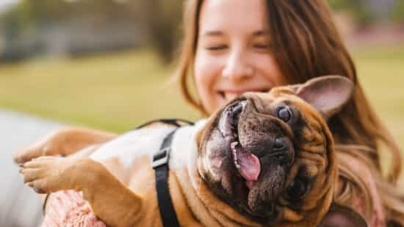 A woman holds a dog outside