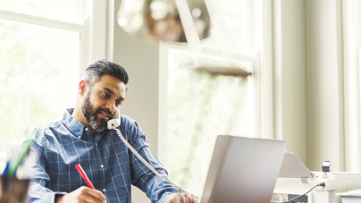 Business professional participating in a pet care franchise discovery call while taking notes.