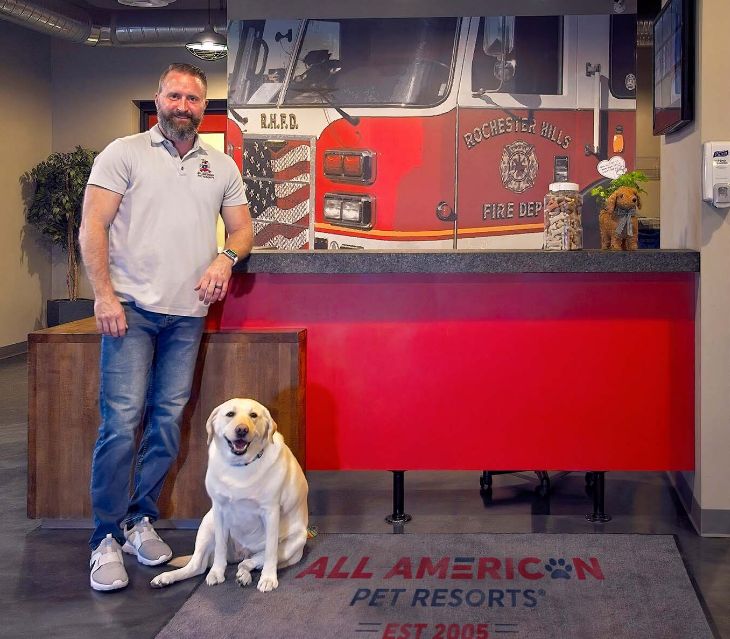 Chris and dog standing in front of red desk