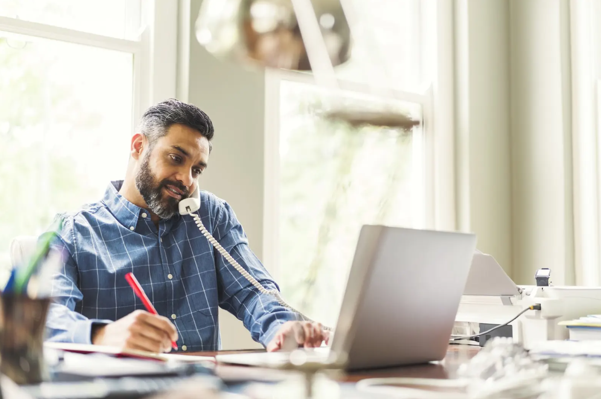Business professional participating in a pet care franchise discovery call while taking notes.